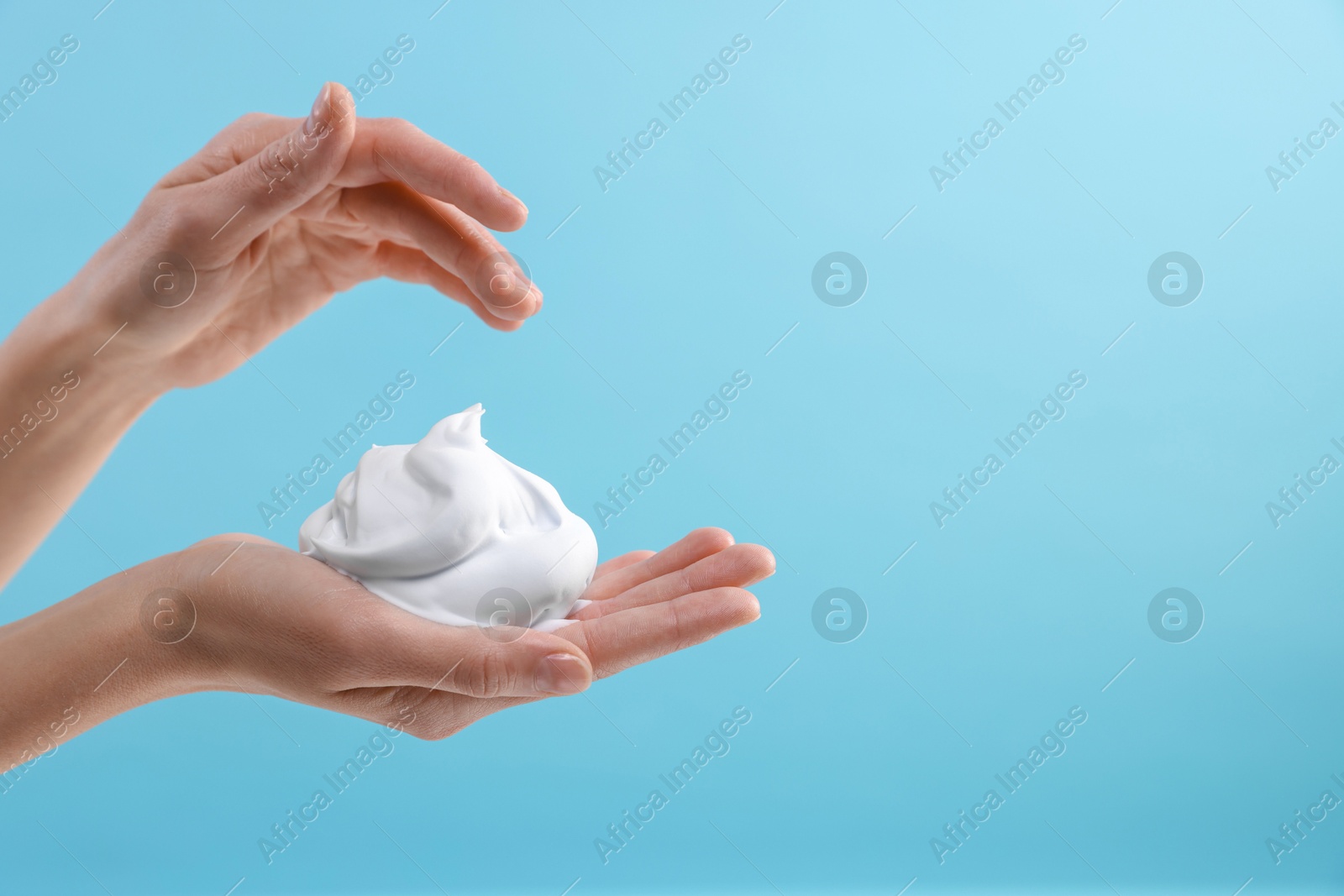 Photo of Woman with cosmetic foam on light blue background, closeup with space for text