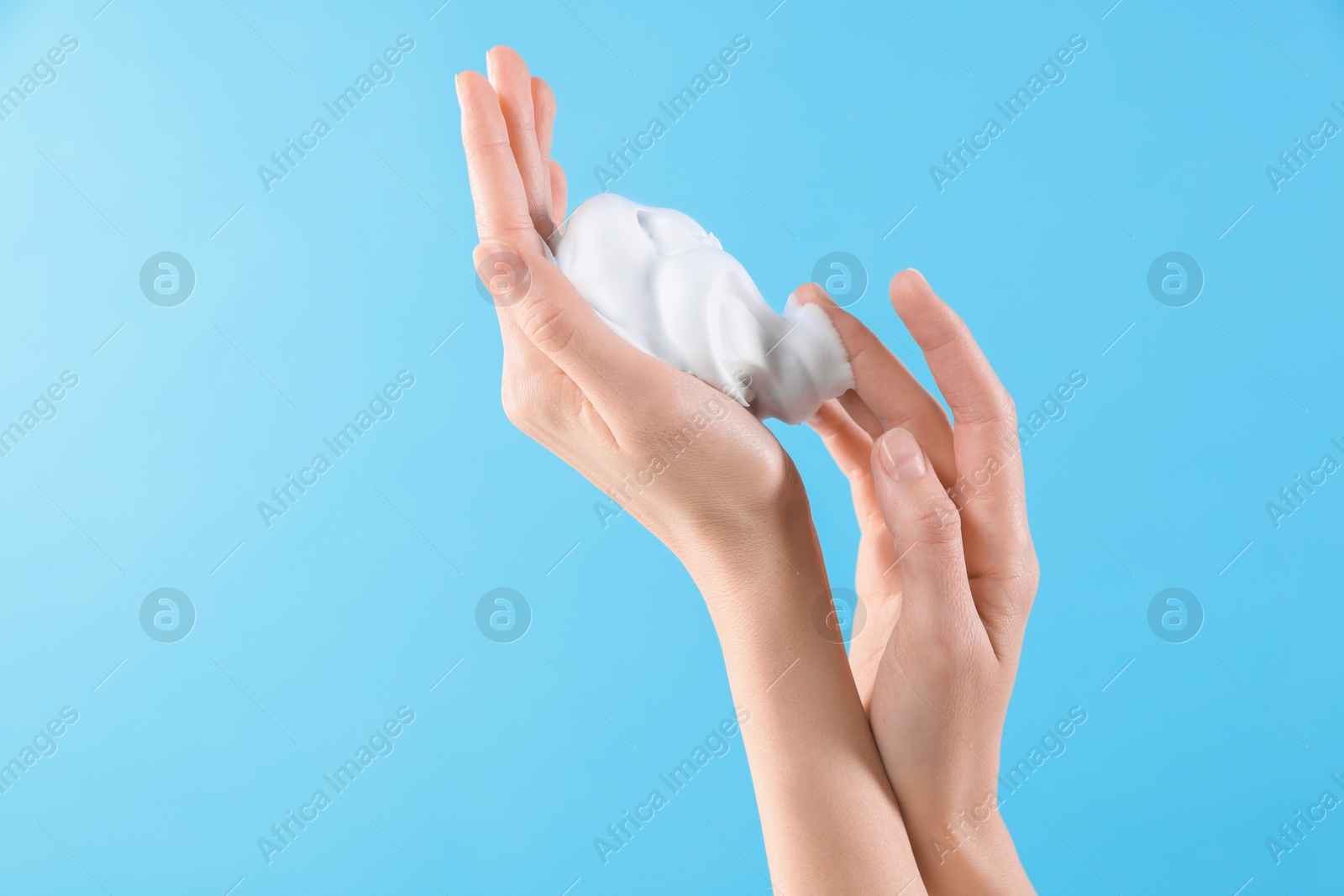 Photo of Woman with cosmetic foam on light blue background, closeup with space for text