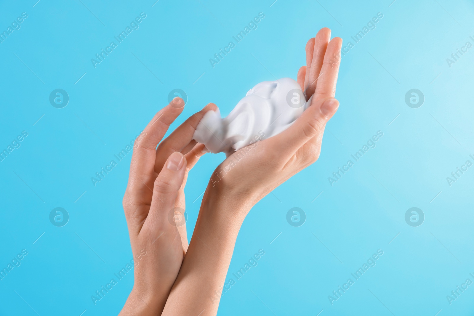 Photo of Woman with cosmetic foam on light blue background, closeup