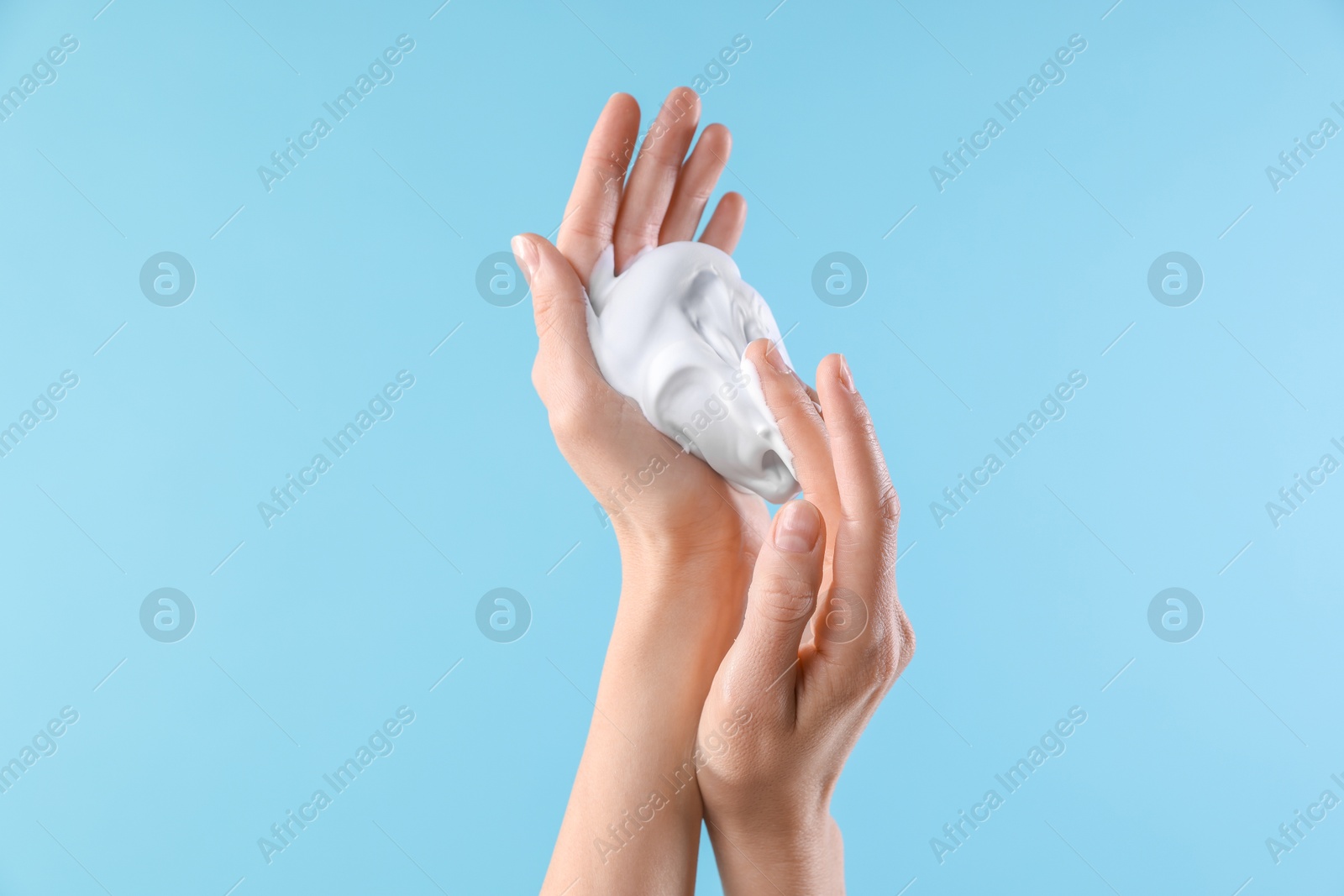 Photo of Woman with cosmetic foam on light blue background, closeup