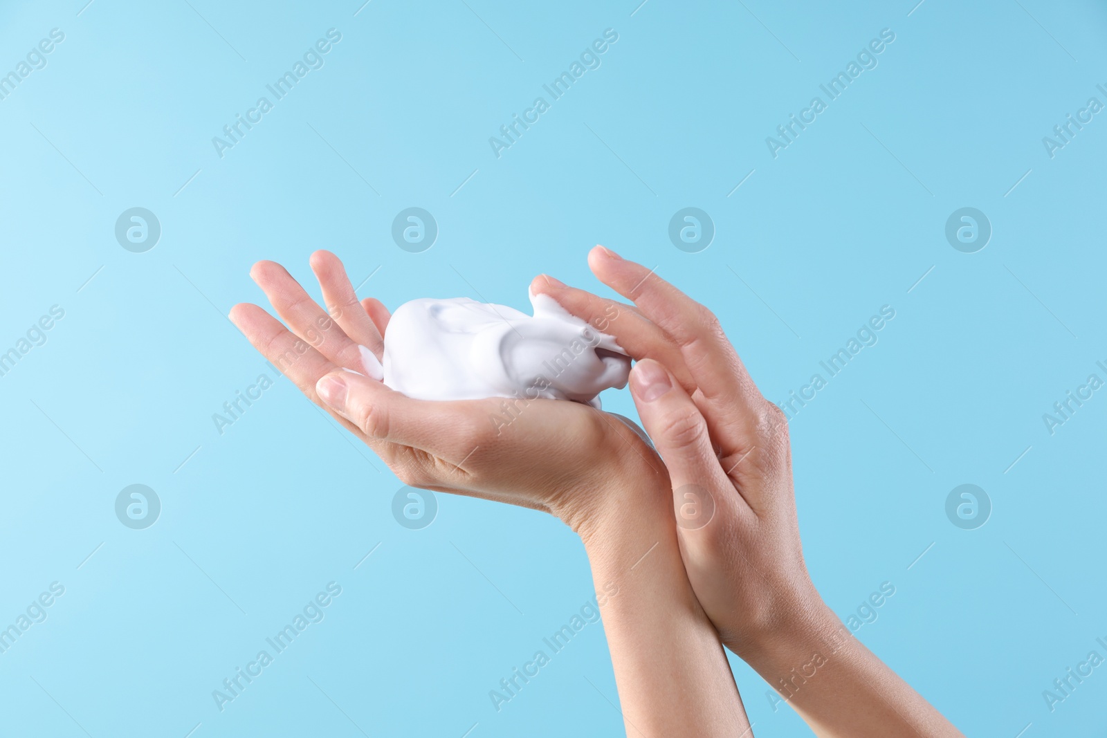 Photo of Woman with cosmetic foam on light blue background, closeup