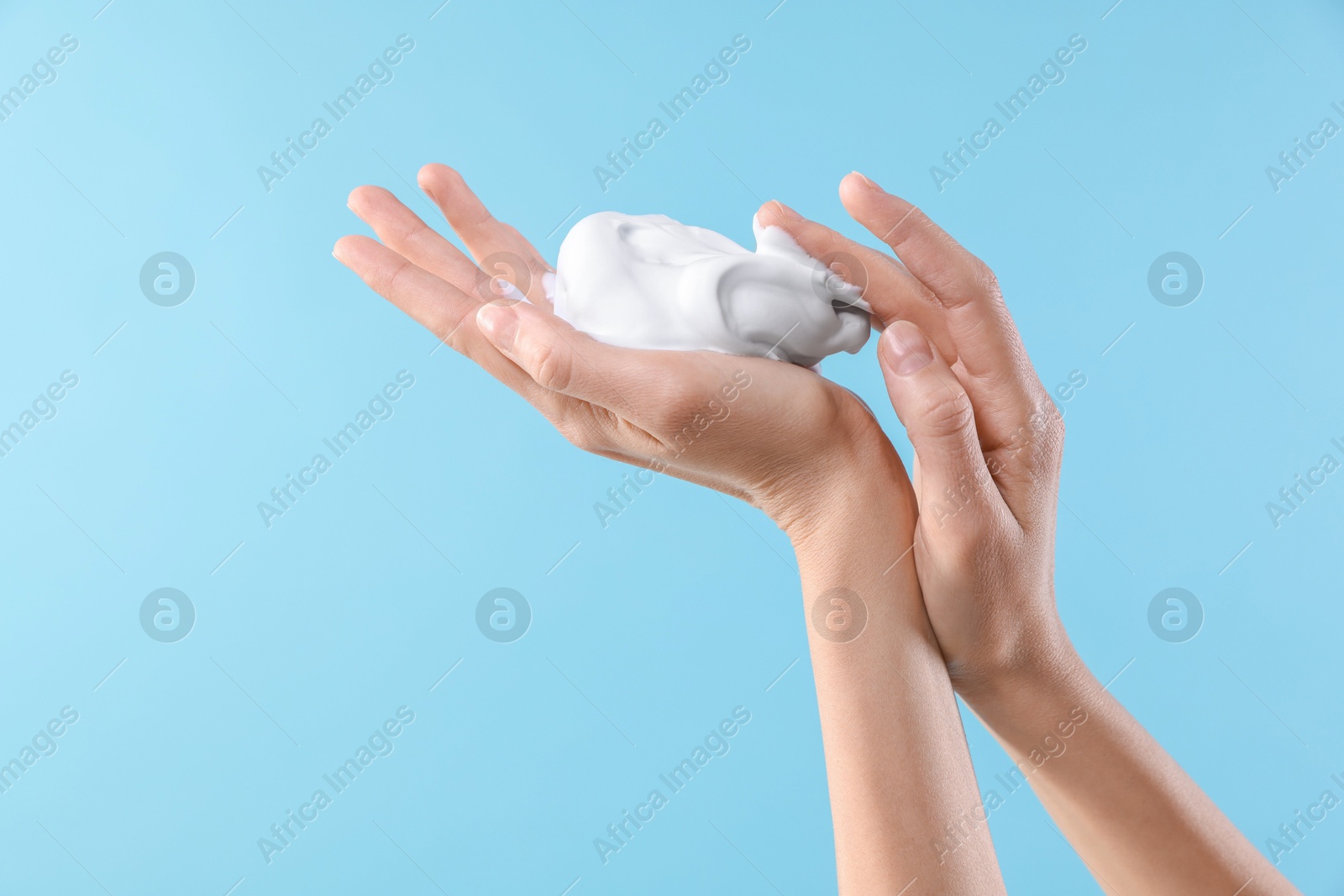 Photo of Woman with cosmetic foam on light blue background, closeup with space for text