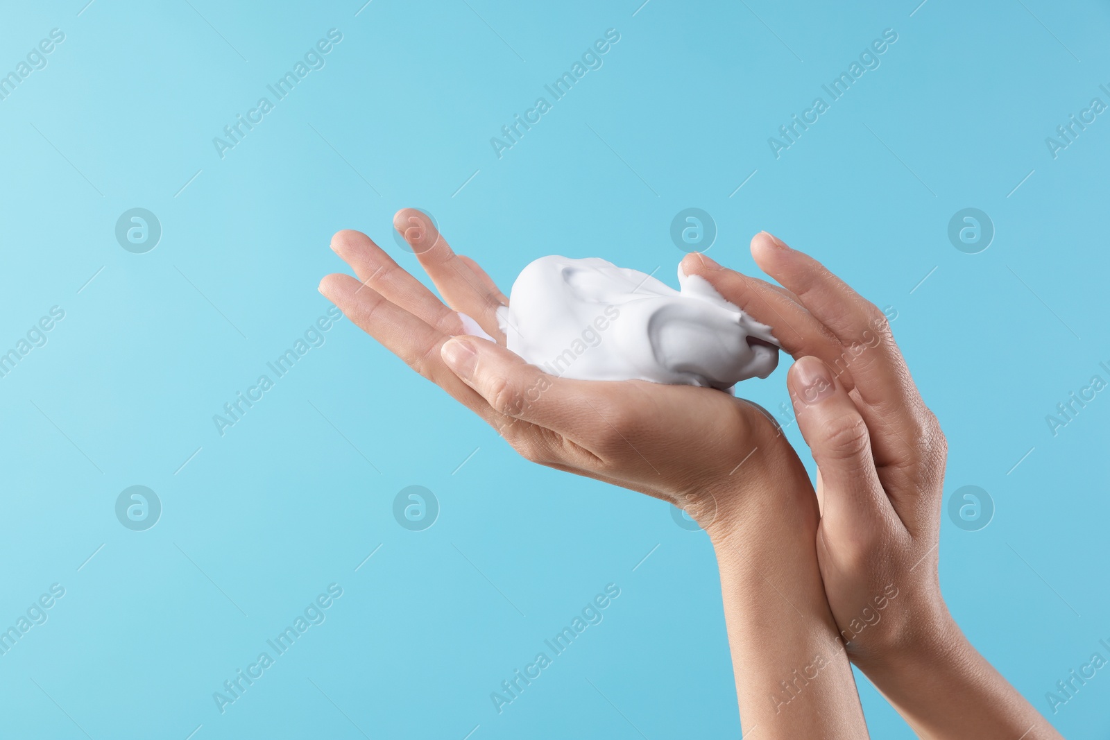 Photo of Woman with cosmetic foam on light blue background, closeup with space for text