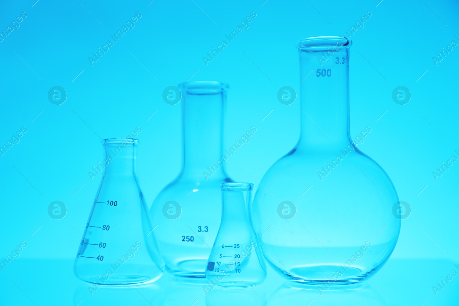 Photo of Empty flasks on light blue background. Laboratory equipment