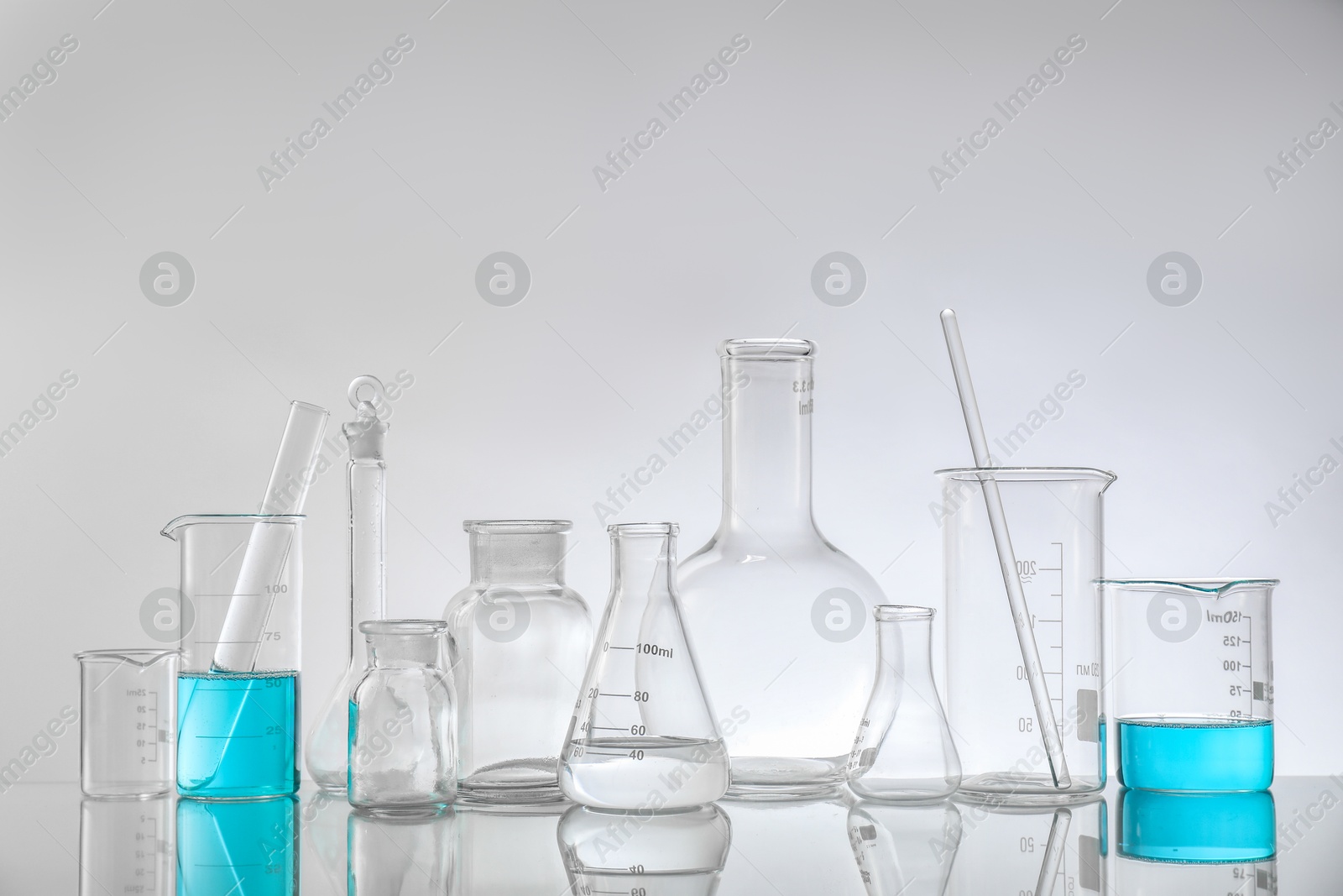 Photo of Laboratory glassware on mirror surface against light background