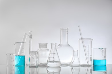 Laboratory glassware on mirror surface against light background