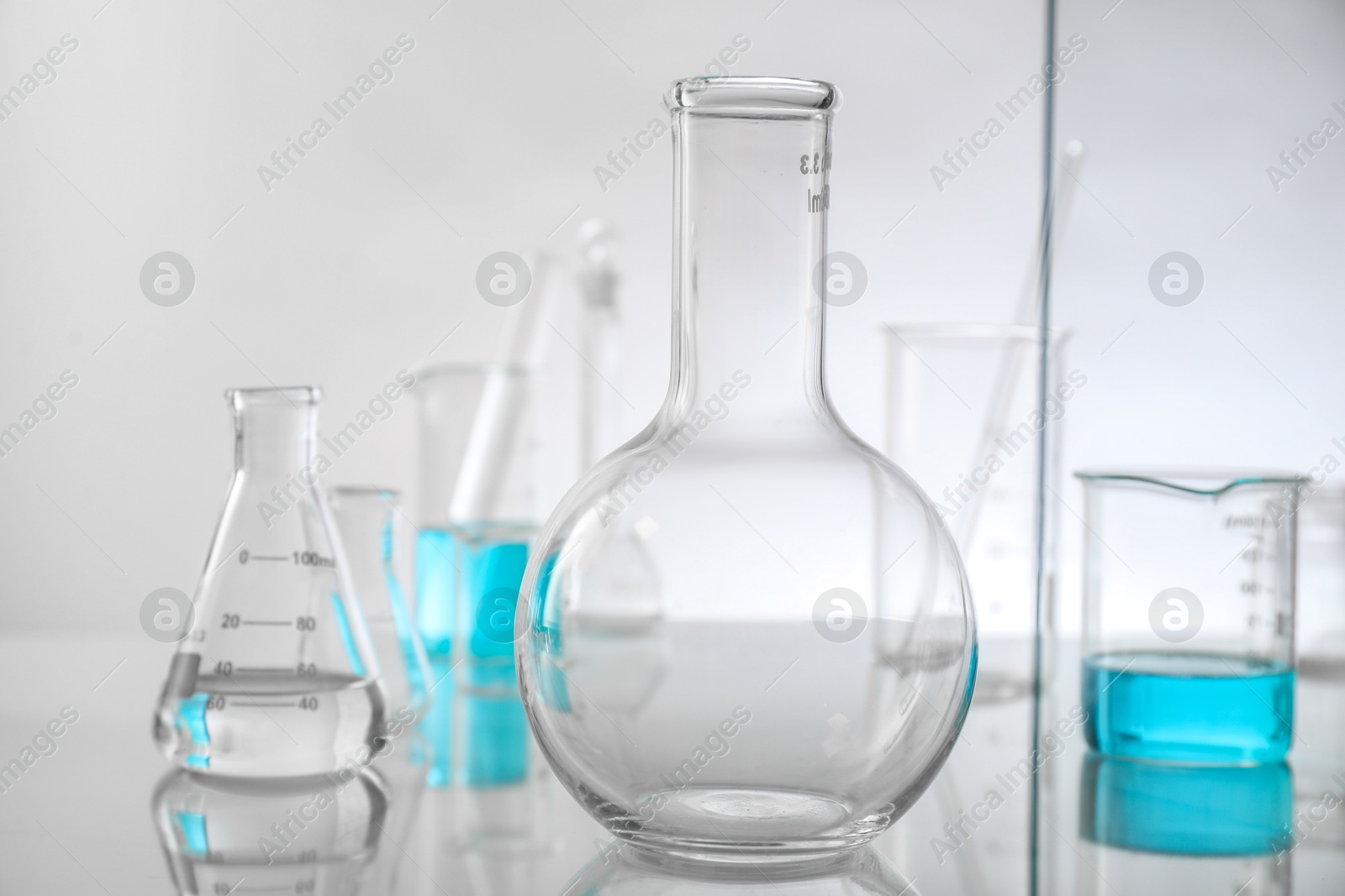 Photo of Laboratory glassware on mirror surface against light background