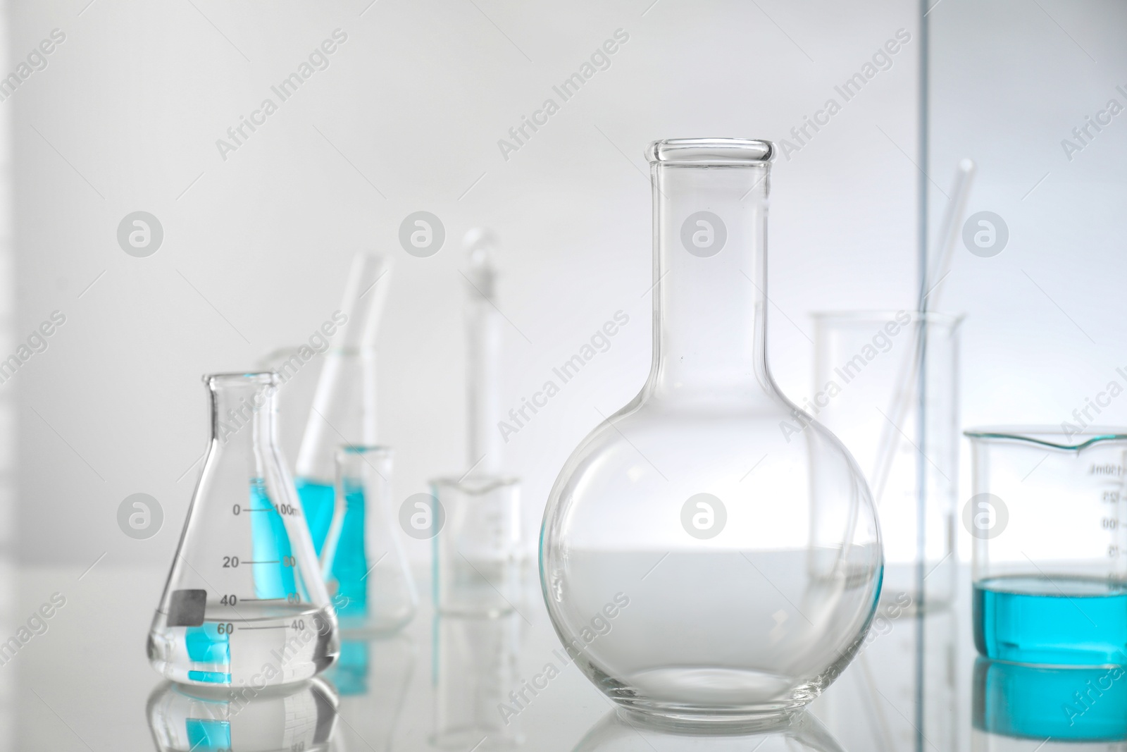 Photo of Laboratory glassware on mirror surface against light background