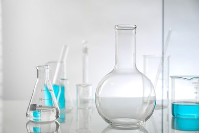 Laboratory glassware on mirror surface against light background