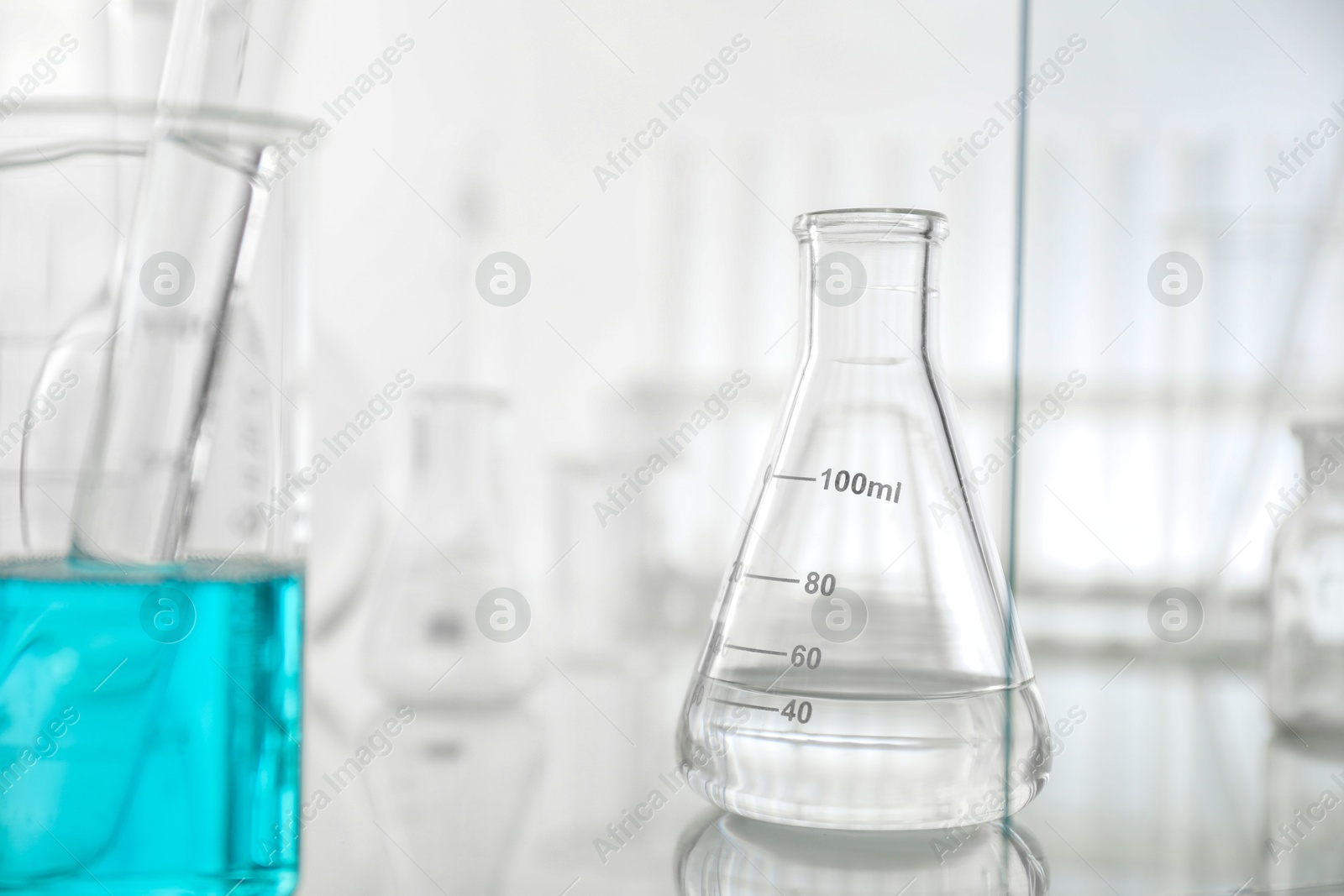 Photo of Laboratory glassware on mirror surface against light background