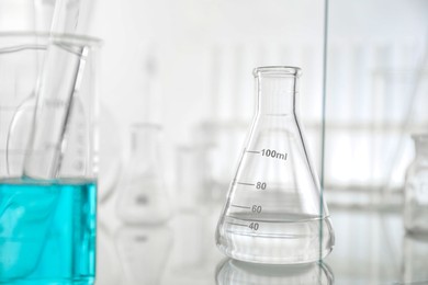 Laboratory glassware on mirror surface against light background