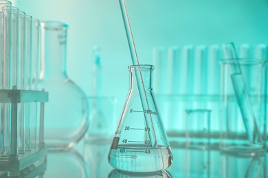 Photo of Laboratory glassware on mirror surface against turquoise background