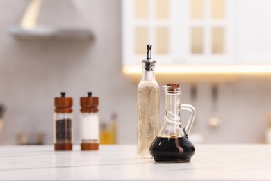 Photo of Bottles of salad dressings, salt and pepper on white table in kitchen, space for text