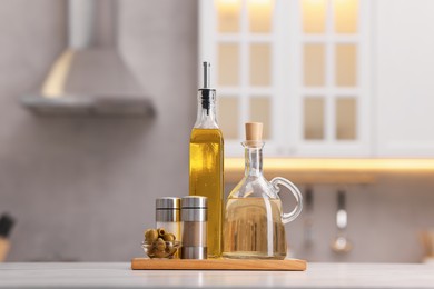 Photo of Bottles of salad dressings, salt, pepper and olives on white table in kitchen