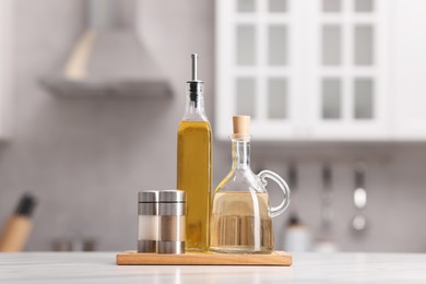 Photo of Bottles of salad dressings, salt and pepper on white table in kitchen