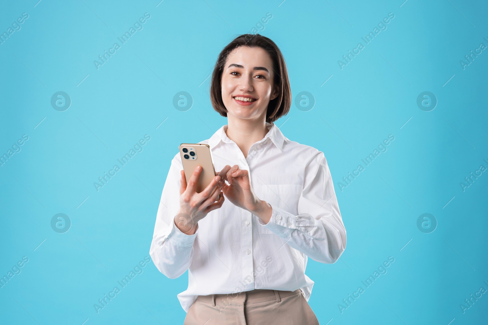 Photo of Smiling secretary using smartphone on light blue background