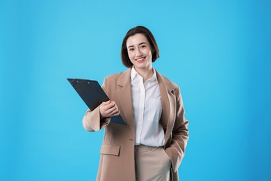 Photo of Portrait of young secretary with clipboard on light blue background