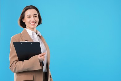 Portrait of young secretary with clipboard on light blue background. Space for text