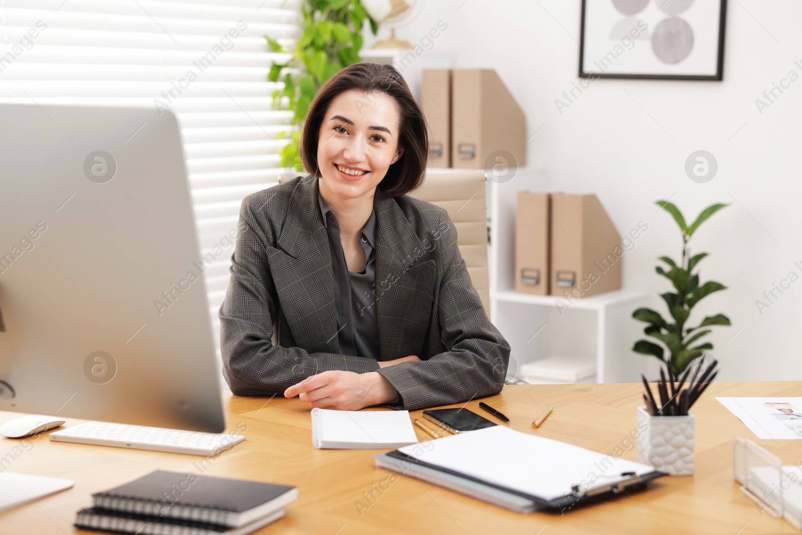 Photo of Portrait of smiling secretary at wooden table in office