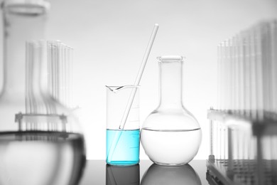 Photo of Laboratory glassware with liquid on mirror surface against light background