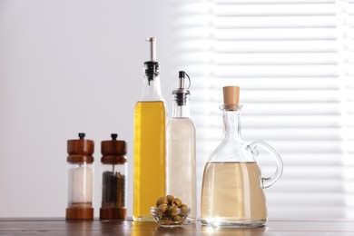 Photo of Salad dressings, spices and olives on table in kitchen