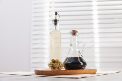 Photo of Salad dressings and olives on table in kitchen