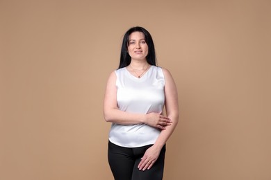 Portrait of smiling plus size model on beige background. Overweight