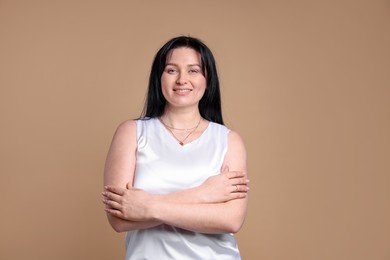 Portrait of smiling plus size model on beige background. Overweight