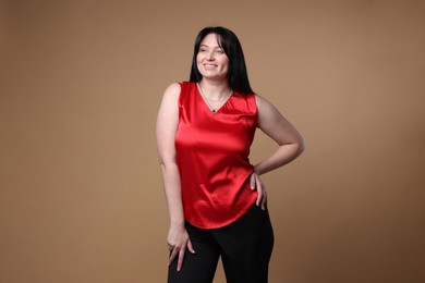 Portrait of smiling plus size model on beige background. Overweight