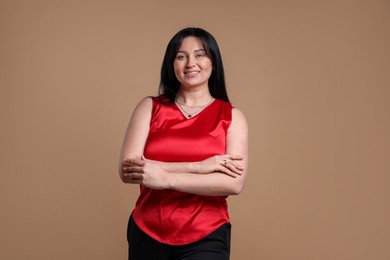 Portrait of smiling plus size model on beige background. Overweight