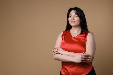 Portrait of smiling plus size model on beige background, space for text. Overweight