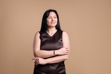 Portrait of smiling plus size model on beige background. Overweight