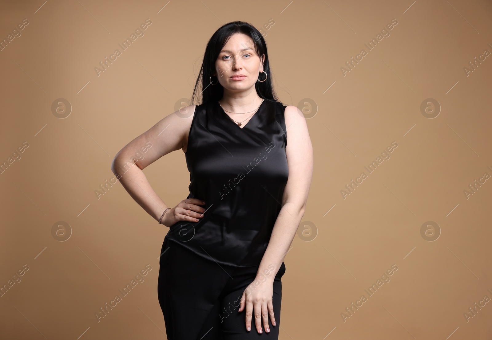 Photo of Portrait of charming plus size model on beige background. Overweight