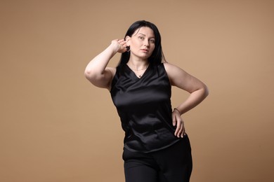 Portrait of charming plus size model on beige background. Overweight