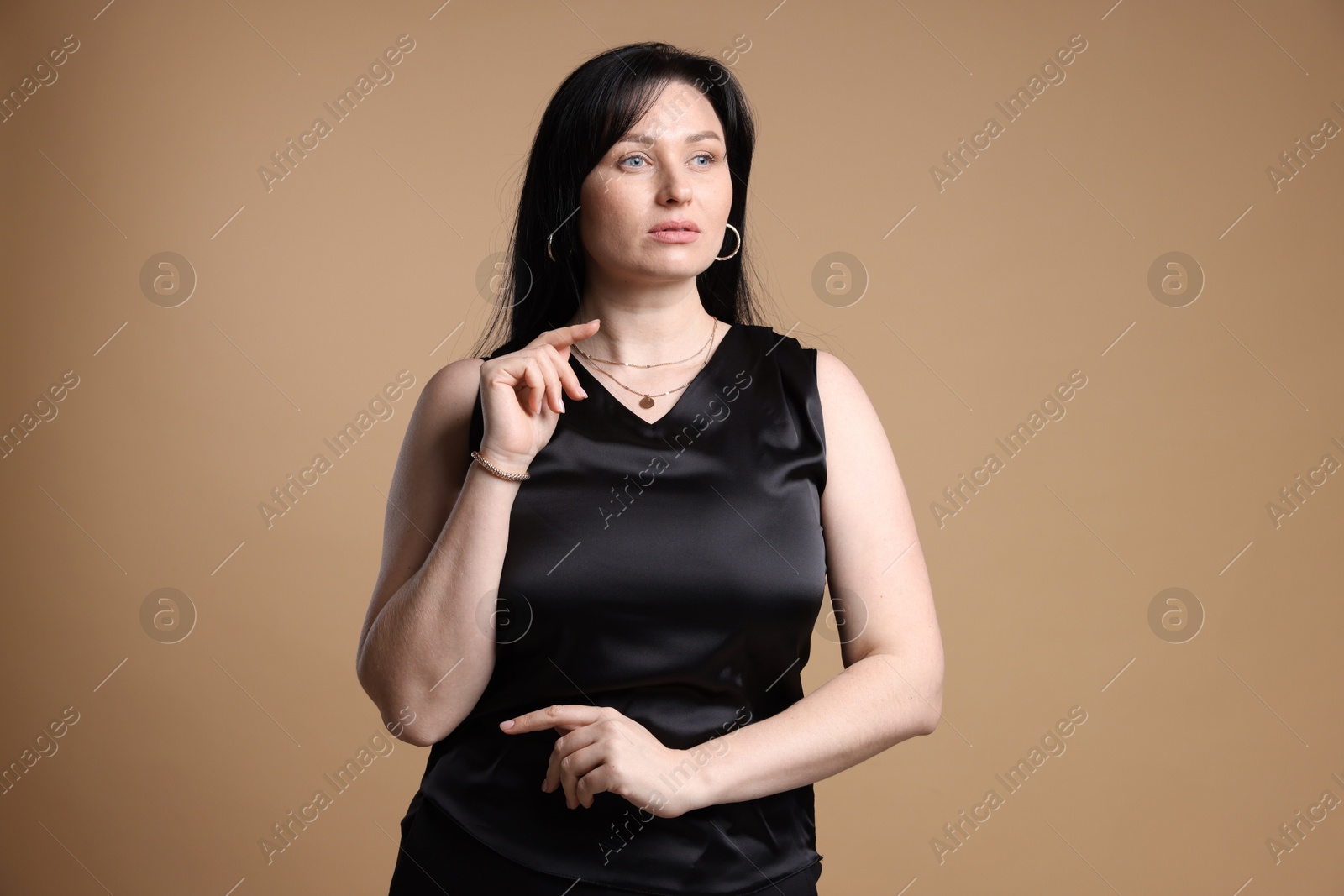 Photo of Portrait of charming plus size model on beige background. Overweight