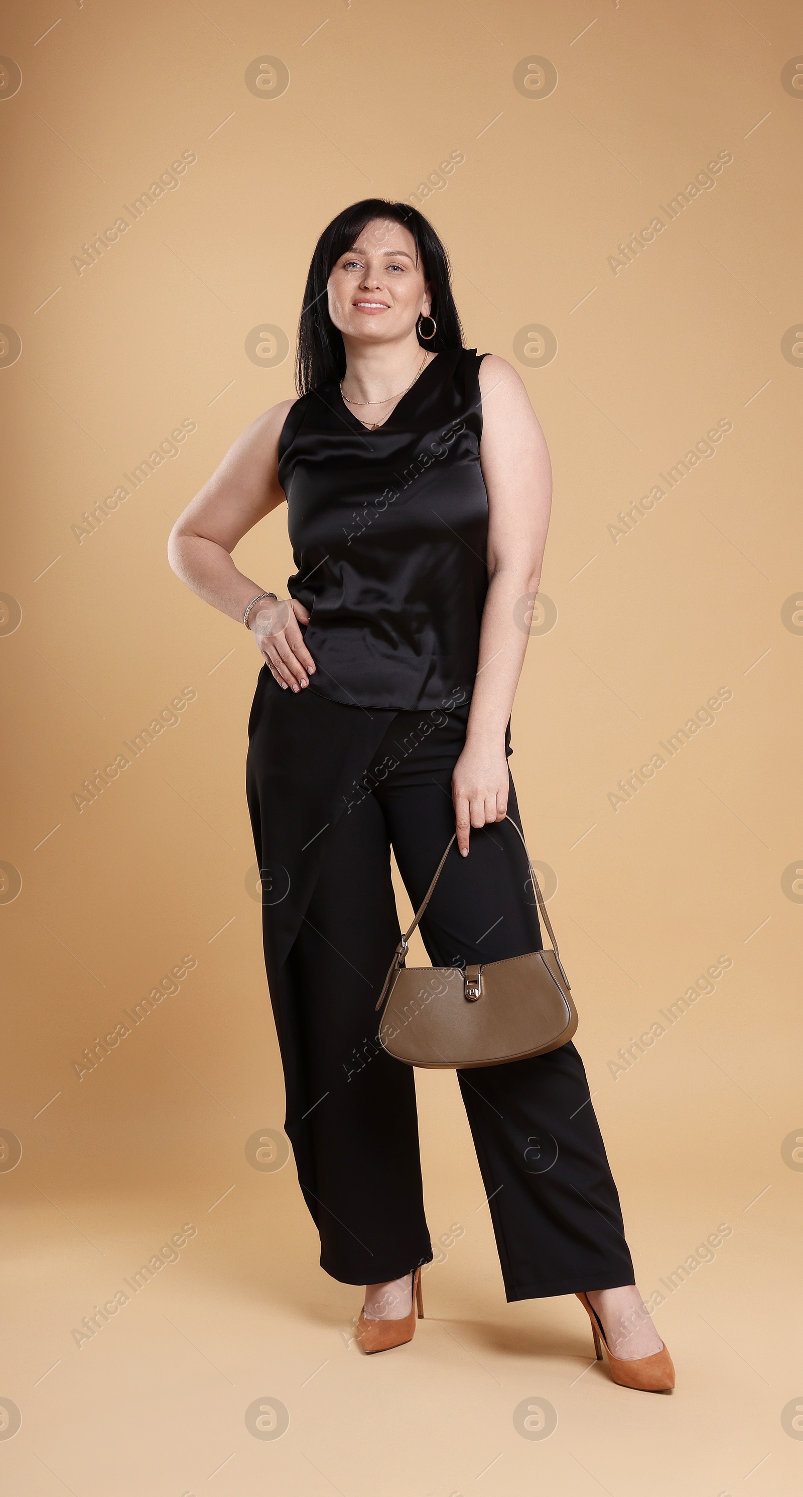 Photo of Smiling plus size model with bag on beige background. Overweight