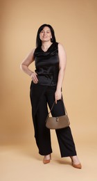 Smiling plus size model with bag on beige background. Overweight