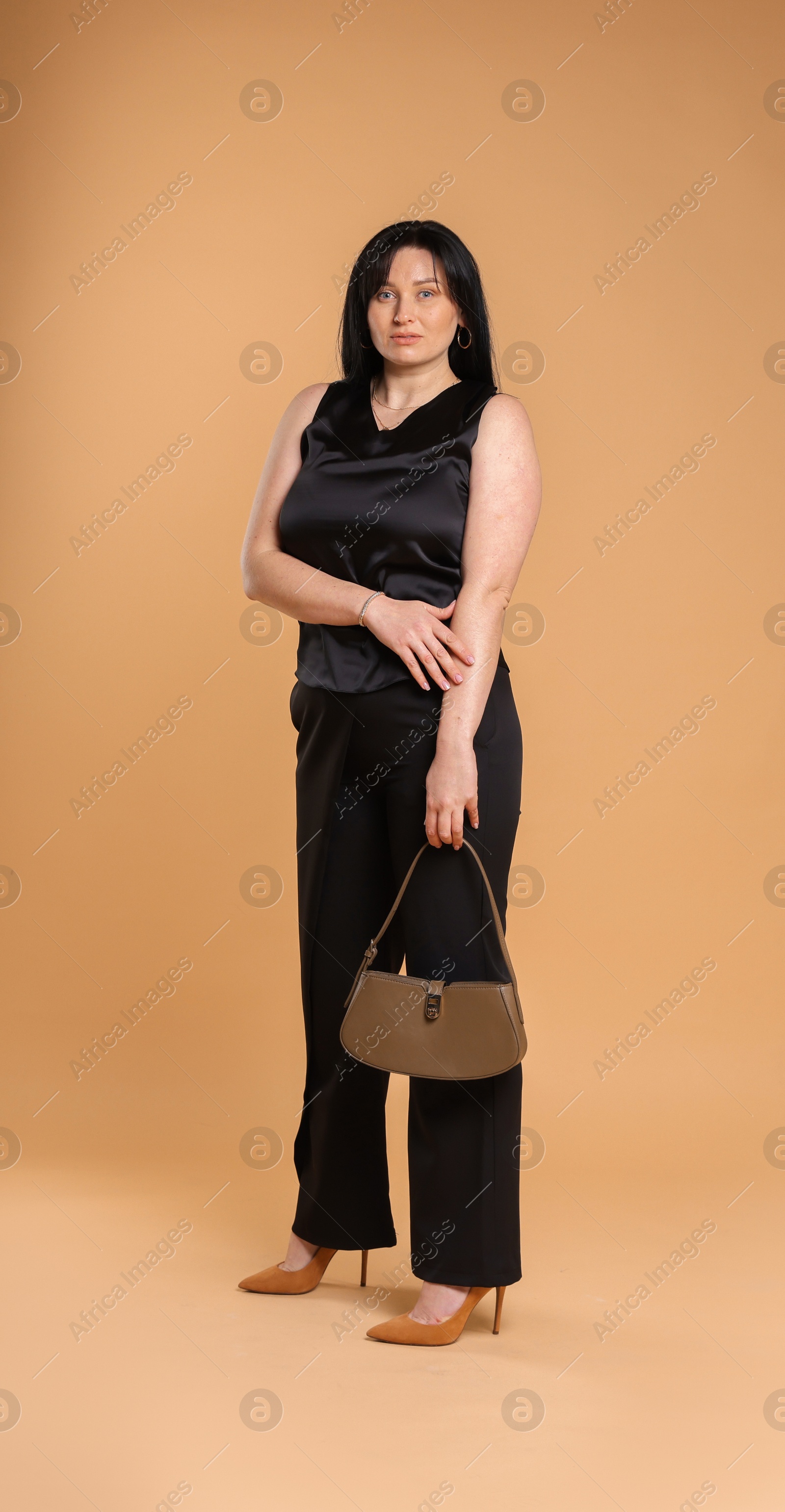 Photo of Elegant plus size model with bag on beige background. Overweight