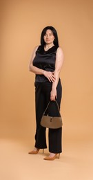 Elegant plus size model with bag on beige background. Overweight