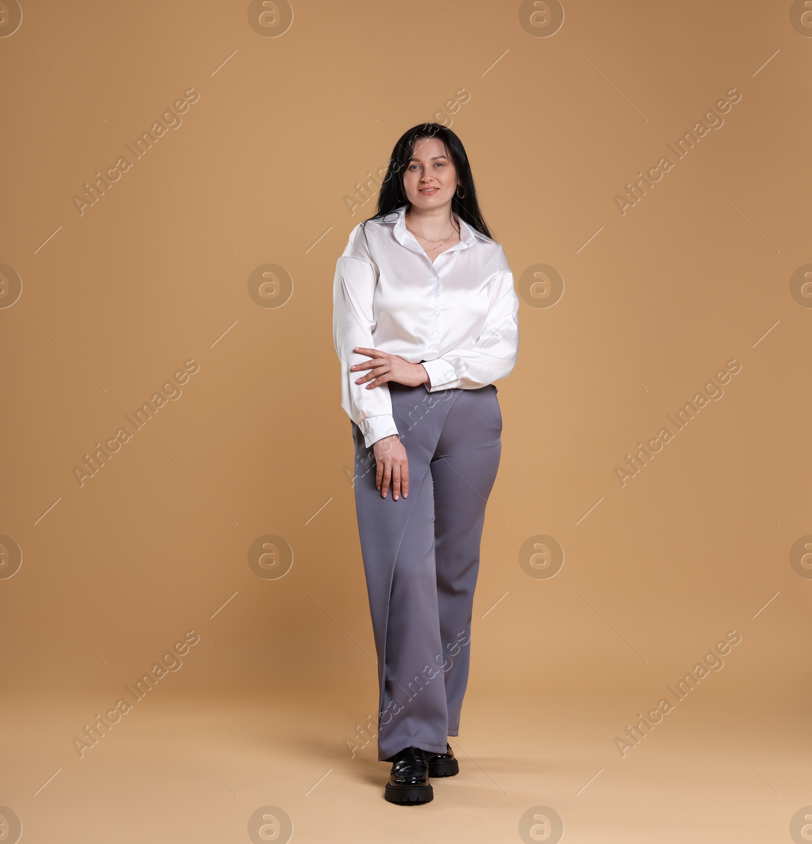 Photo of Smiling plus size model on beige background. Overweight