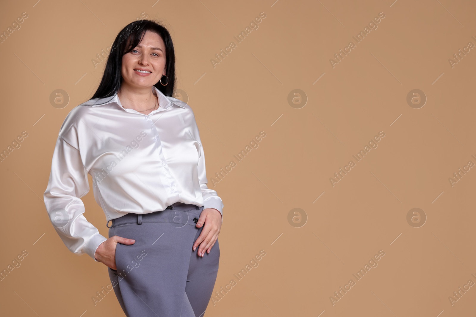 Photo of Portrait of smiling plus size model on beige background, space for text. Overweight