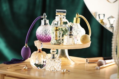 Photo of Different luxury perfumes on wooden dressing table indoors