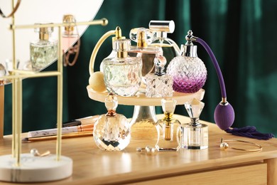 Photo of Different luxury perfumes on wooden dressing table indoors