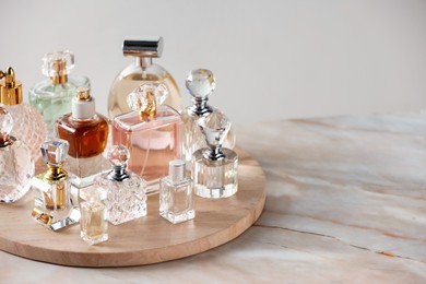 Photo of Different luxury perfumes on color marble table, closeup. Space for text