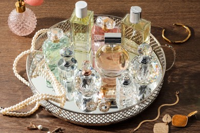 Photo of Different luxury perfumes and accessories on wooden table