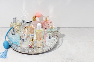 Photo of Different luxury perfumes and accessories on light textured table, space for text