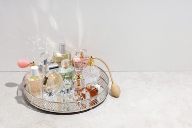 Photo of Different luxury perfumes and accessories on light textured table, space for text