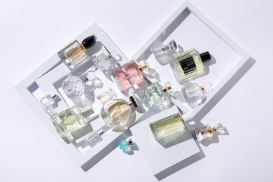 Photo of Different luxury perfumes on white background, flat lay