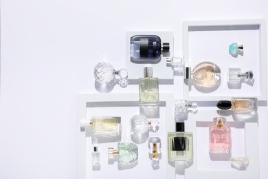 Photo of Different luxury perfumes on white background, flat lay