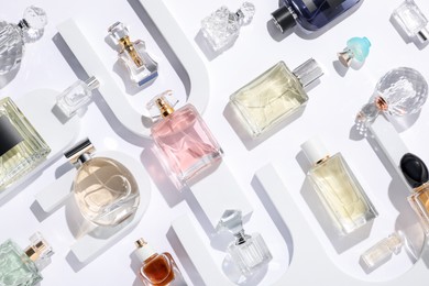 Photo of Different luxury perfumes on white background, flat lay